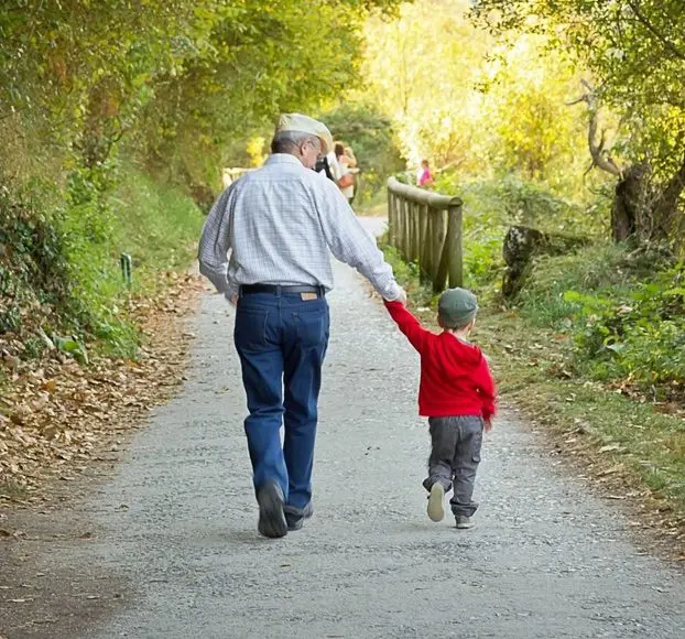 A man and boy walking down the road holding hands.